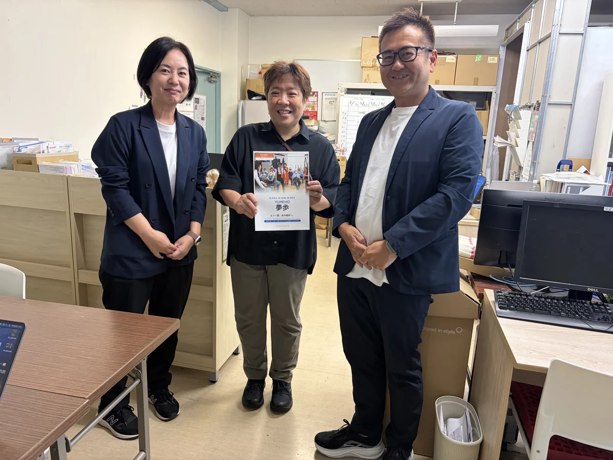 YUMEHO（夢歩）のカタログを手にする下元佳子代表と当社メンバー