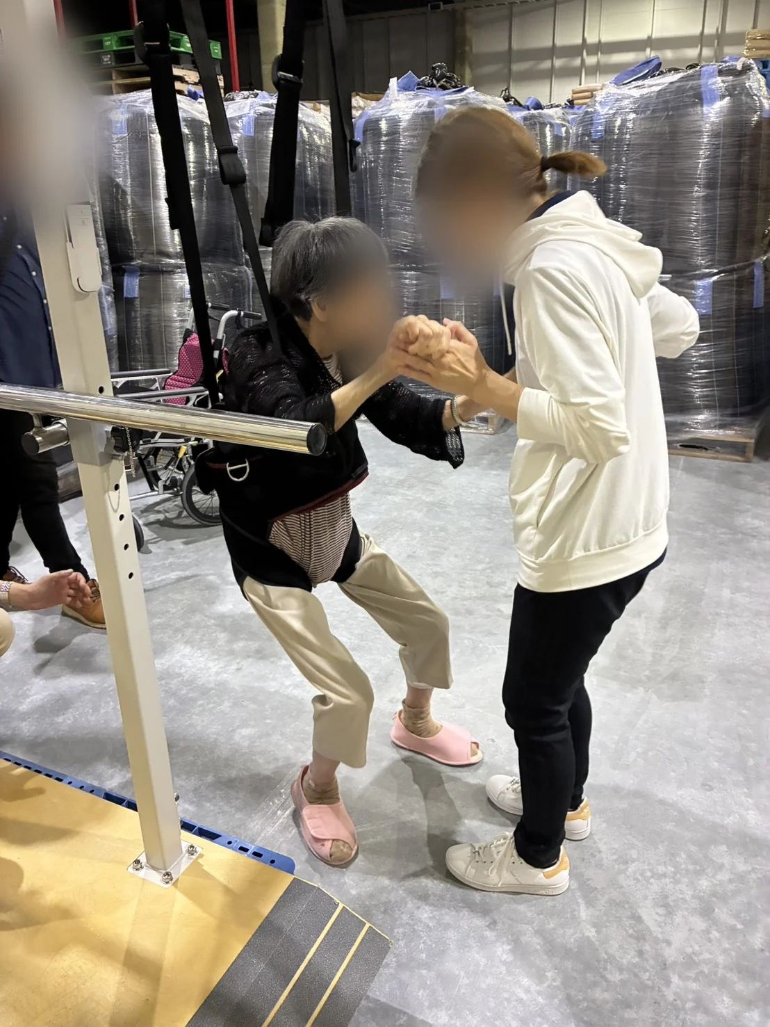YUMEHOで歩き、職員と喜びを分かち合うご利用者。背景を含め顔をぼかして掲載